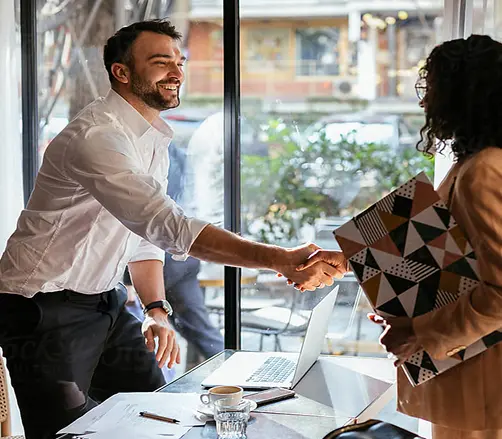 Businessman and businesswoman shaking hands during a meeting in a bright office